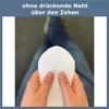Hands holding a white sock, with a person's legs in blue jeans in the background. Produktbild-Vorschau