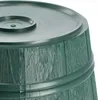 A close-up view of the top section of a green, barrel-shaped object, likely a Christmas tree stand, showing its textured surface and a raised circular detail on the lid. Voir les images du produit