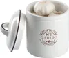 A white ceramic garlic keeper with a lid slightly ajar, filled with garlic bulbs. Produktbild-Vorschau