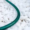 A green garden hose lies on a bed of white gravel. Anteprima dell’immagine prodotto