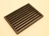 A dark metal grate with multiple parallel slots, placed on a light-colored surface. Podgląd zdjęcia produktu