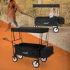 A woman is pulling a black HAUKI wagon with a child in it on a dirt path.
