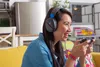 A woman playing a video game with headphones and a controller. Produktbild-Vorschau