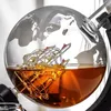 A close-up shot of a globe-shaped decanter filled with amber liquid and a glass ship inside. Náhľad obrázku produktu