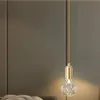 A pendant light with a gold fixture and a clear, textured bulb hangs against a textured gray wall. Produktbild-Vorschau