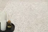 A close-up of a beige rug with a classic pattern, with two white candles and a diffuser on a black tray in the foreground. Produktbild-Vorschau
