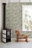 A cozy room corner with a wood-burning stove, a rocking horse, and a window with plants. Produktbild-Vorschau