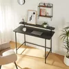 A black desk with a laptop, mug, and artwork is shown in a well-lit room with a chair and a plant. Náhľad obrázku produktu