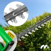 Close-up of a hedge trimmer cutting green foliage, with a magnified view of the blades and a detail of the handle with safety symbols. Náhľad obrázku produktu