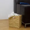 Papierbraune Knitterbox mit Decke neben einer Couch im Wohnzimmer Produktbild-Vorschau