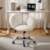 A white fluffy office chair is placed in front of a white desk with a laptop and books on it. The scene is set in a room with wooden floors and sheer curtains in the background. Produktbild-Vorschau