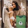 A mother and baby are in a laundry room with a washing machine and a toy bin. Náhled obrázku produktu