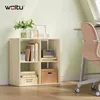 A light wood cube shelf unit filled with books, decorative items, and storage boxes, placed next to a desk with a chair in a room with light green walls. Produktbild-Vorschau