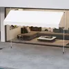 A white awning is set up on a patio in front of a modern house with large glass windows. Inside the house, a sectional sofa and coffee table are visible. Anteprima dell’immagine prodotto