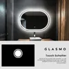 A modern bathroom with a lit oval mirror above a sink, and a separate graphic showing a touch switch icon. Produktbild-Vorschau