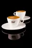 Two cups of coffee with latte art on saucers, reflected on a black surface. Náhled obrázku produktu