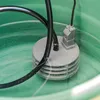 A close-up of a submersible pump with a black hose and power cord submerged in green water within a container. Produktbild-Vorschau
