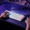 A person's hands are shown typing on a white mechanical keyboard with RGB lighting, in front of a computer monitor displaying a video game. Produktbild-Vorschau