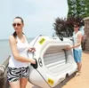 A man and a woman are holding an inflatable boat on a patio near the water. Anteprima dell’immagine prodotto