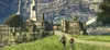 Two people walk along a grassy path towards a large, ancient-looking structure with towers. Produktbild-Vorschau