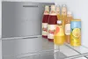 Several bottles and a can of drinks are arranged on a shelf inside a refrigerator. Produktbild-Vorschau