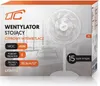 The image shows the front of a product box for a white standing fan. The box features product details and branding. Voir les images du produit