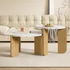 Two round coffee tables with terrazzo-like tops and wooden legs are placed on a rug in front of a tufted sofa. Voir les images du produit
