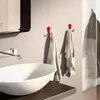 A modern bathroom scene with a sink, faucet, and red towel hooks. Produktbild-Vorschau