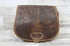 A brown leather bag with a deer embossed on it, placed on a wooden surface. Podgląd zdjęcia produktu