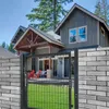 A metal garden gate in front of a modern house with a lawn and trees. Produktbild-Vorschau