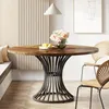A round dining table with a wooden top and a metal base, set in a dining area with chairs and a wall paneling. Podgląd zdjęcia produktu