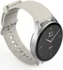 A smartwatch with a silver casing and a white strap is shown against a white background. Produktbild-Vorschau