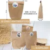 A collection of brown paper bags with decorative stickers, along with a stack of similar bags and some dried grass. Produktbild-Vorschau