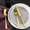 A set of gold cutlery is laid out on plates with a purple napkin. Podgląd zdjęcia produktu