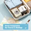 A travel kettle is packed inside an open suitcase along with clothes, sunglasses, a map, and a watch. Produktbild-Vorschau