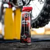 A can of K2 Off-Road Chain Lube is shown in front of a motorcycle wheel and yellow equipment. Produktbild-Vorschau