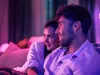 A couple is sitting on a couch, illuminated by colorful ambient lighting, possibly watching something. Anteprima dell’immagine prodotto