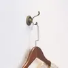A vintage-style bronze wall hook with a silver hanger and a wooden coat hanger attached. Produktbild-Vorschau