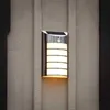 A solar-powered LED wall light is mounted on a textured wall. Podgląd zdjęcia produktu