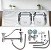 A stainless steel double sink with a draining board, shown from a slightly elevated front view, with plumbing accessories laid out below. Anteprima dell’immagine prodotto