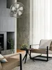 A wall-mounted fan is displayed in a modern living room setting, next to a fireplace and chairs. Podgląd zdjęcia produktu