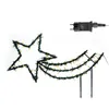 A star-shaped light decoration with a trailing tail, illuminated with warm white LEDs, and a power adapter. The decoration has stakes for garden placement. Produktbild-Vorschau