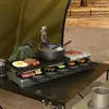 A raclette grill set up on a table outdoors, possibly while camping, with food being cooked. Náhľad obrázku produktu