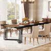 A dining room scene with a large wooden dining table set for a meal, surrounded by chairs, with a chandelier overhead and a large window in the background. Náhled obrázku produktu