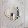 A decorative wall mirror with a gold frame is mounted on a light gray wall with decorative molding. Produktbild-Vorschau