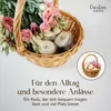 A woven basket filled with flowers and small tins, with a smaller inset image of a similar basket. Produktbild-Vorschau