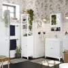 A well-lit bathroom featuring a white vanity cabinet with a sink, a tall white storage cabinet, a mirror, and various bathroom accessories. Produktbild-Vorschau