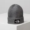 A grey knitted beanie with a black and white logo patch. Produktbild-Vorschau