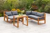 Outdoor patio furniture set with a sofa, loveseat, and coffee table, set against a backdrop of garden plants and flowers. Produktbild-Vorschau
