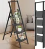 A black folding stepladder with three steps, decorated with flowers and plants, is shown in a living room setting. A separate image of the stepladder in its folded state is on the right. Voir les images du produit